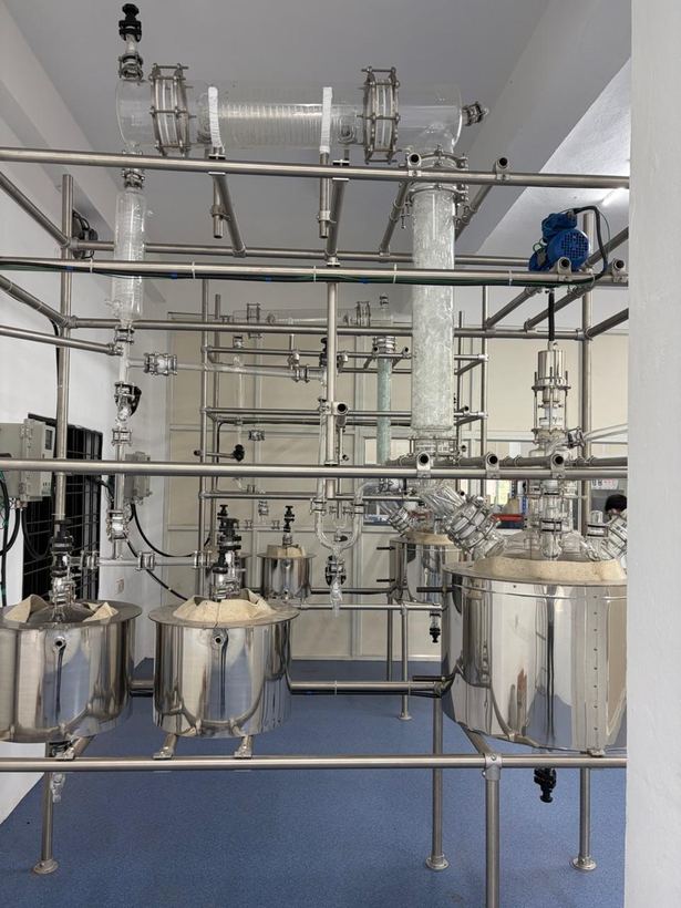 Glass distillation assembly with stainless steel receivers on a framed skid